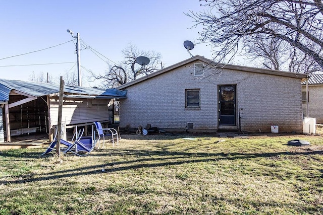 rear view of house with brick siding and a yard