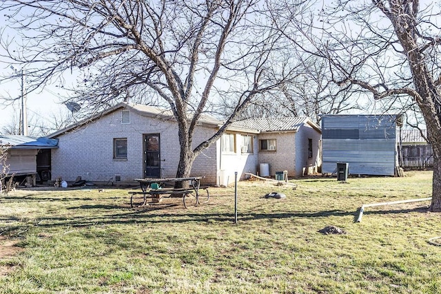 rear view of house featuring brick siding and a lawn