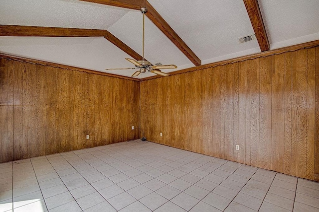 empty room featuring lofted ceiling with beams, wood walls, ceiling fan, and visible vents