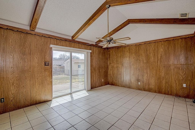 empty room with vaulted ceiling with beams, light tile patterned floors, visible vents, wood walls, and ceiling fan