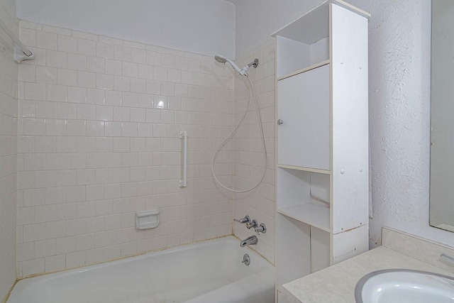 full bathroom featuring a textured wall, shower / tub combination, and vanity