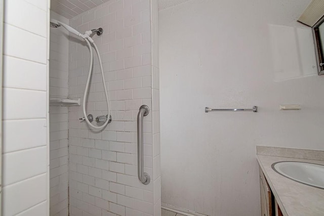 full bath with tiled shower and vanity