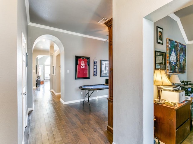 hallway featuring baseboards, visible vents, arched walkways, dark wood-style floors, and ornamental molding