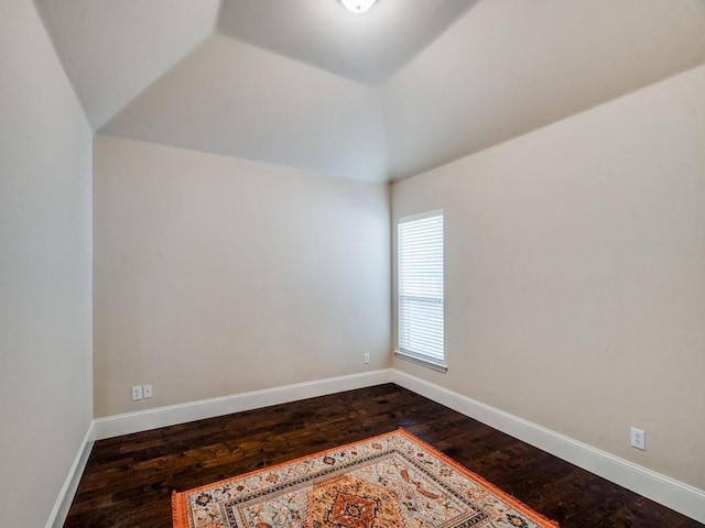 empty room with dark wood-type flooring, vaulted ceiling, and baseboards