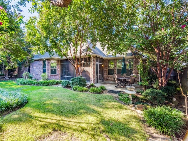 rear view of property featuring a patio, brick siding, a lawn, and a sunroom