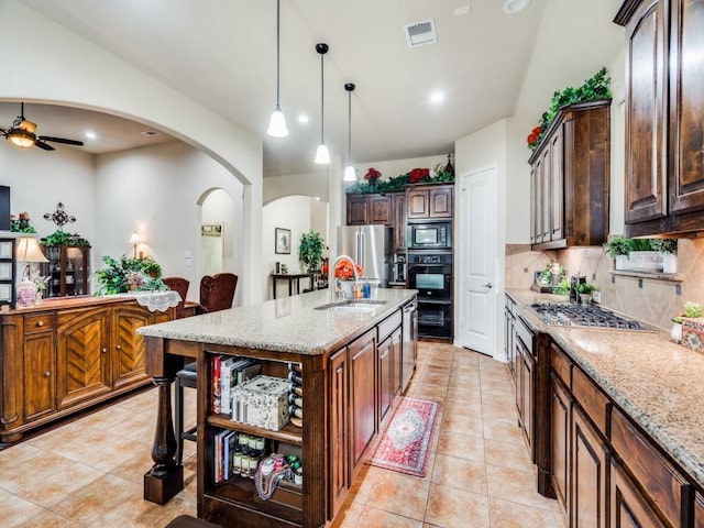 kitchen featuring arched walkways, open shelves, stainless steel appliances, visible vents, and a sink