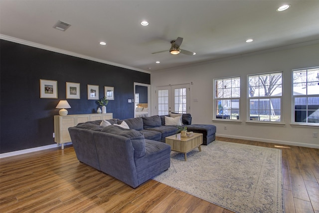 living room with baseboards, wood finished floors, visible vents, and crown molding