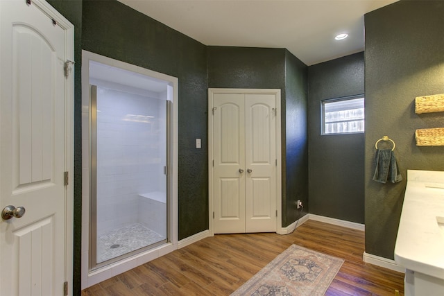 bathroom with a stall shower, wood finished floors, and baseboards