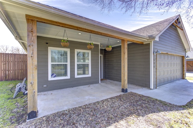 exterior space featuring roof with shingles, fence, driveway, and an attached garage