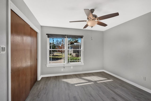 interior space with a ceiling fan, baseboards, and wood finished floors