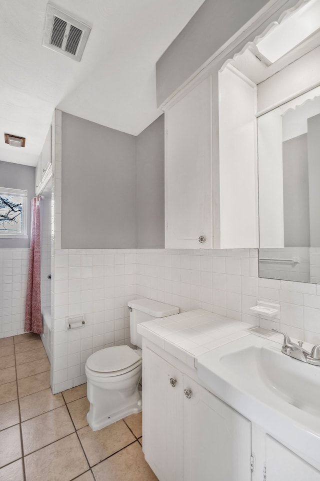 full bathroom featuring tile walls, visible vents, toilet, vanity, and tile patterned flooring