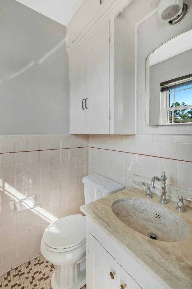 bathroom with toilet, tile walls, and vanity