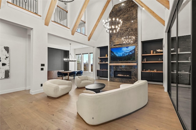 living room featuring high vaulted ceiling, a premium fireplace, a chandelier, and wood finished floors