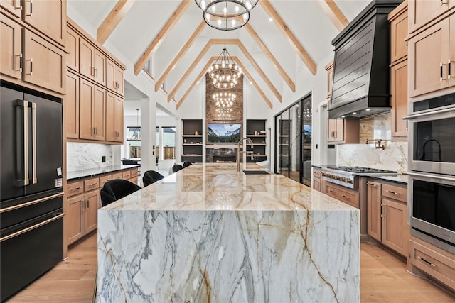 kitchen featuring appliances with stainless steel finishes, a sink, light wood-style flooring, and an inviting chandelier