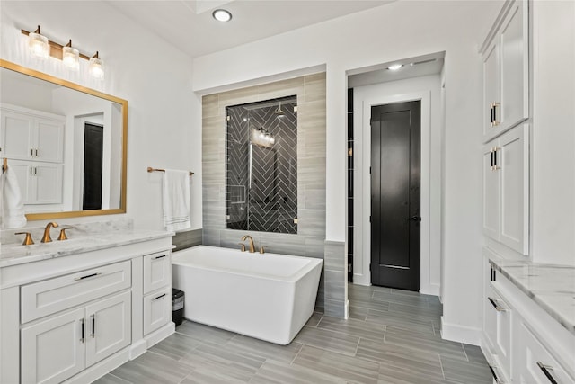 full bathroom with a freestanding tub, recessed lighting, tile walls, and vanity