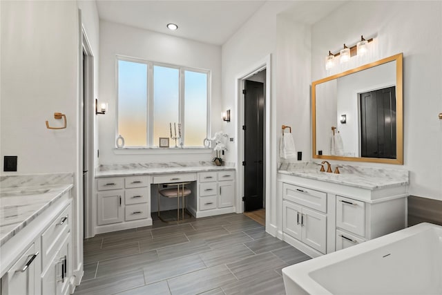 full bathroom with wood tiled floor, two vanities, a freestanding bath, and a sink