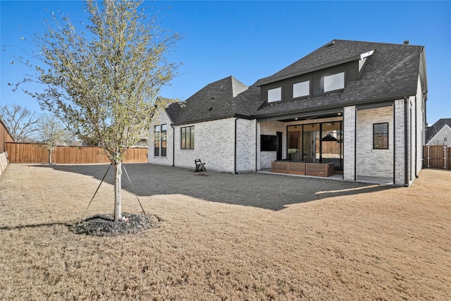 rear view of property with brick siding, a shingled roof, and a fenced backyard