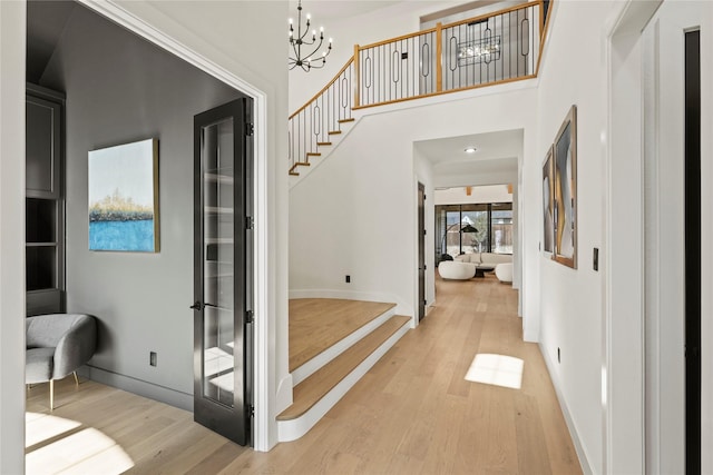 foyer entrance with a chandelier, light wood-type flooring, baseboards, and stairs