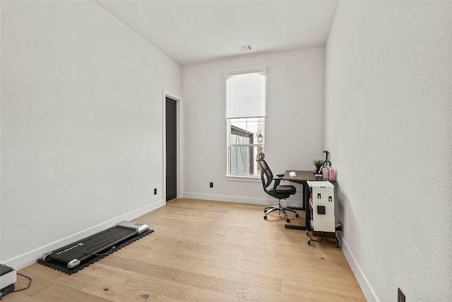 home office featuring light wood-type flooring, visible vents, and baseboards