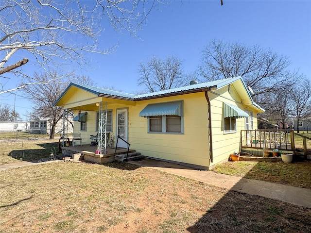 bungalow-style house with covered porch, metal roof, and a front yard