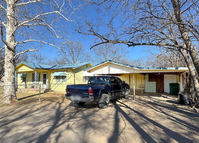 single story home with a carport, concrete driveway, and fence