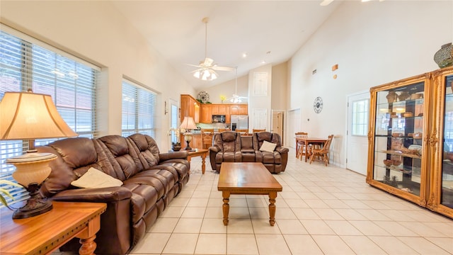 living area with a healthy amount of sunlight, ceiling fan, high vaulted ceiling, and light tile patterned flooring