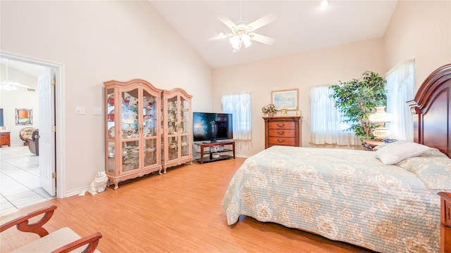 bedroom with ceiling fan, high vaulted ceiling, baseboards, light wood finished floors, and ensuite bath