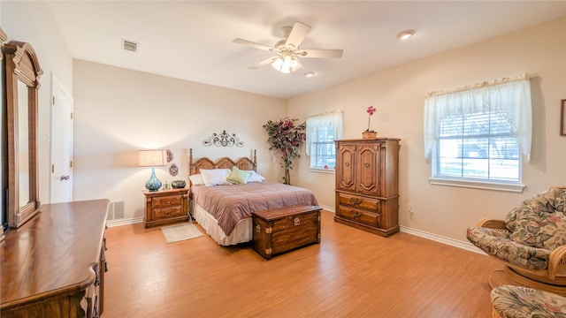 bedroom featuring light wood-style floors, baseboards, visible vents, and a ceiling fan