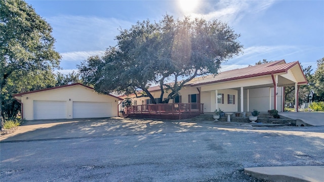 ranch-style house with a garage, covered porch, metal roof, and an outbuilding