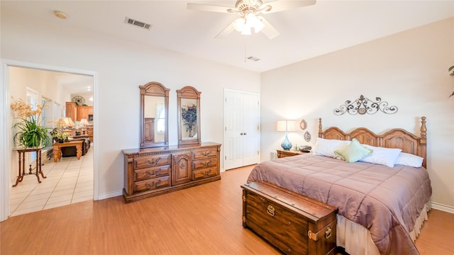 bedroom featuring light wood-type flooring, baseboards, visible vents, and a ceiling fan