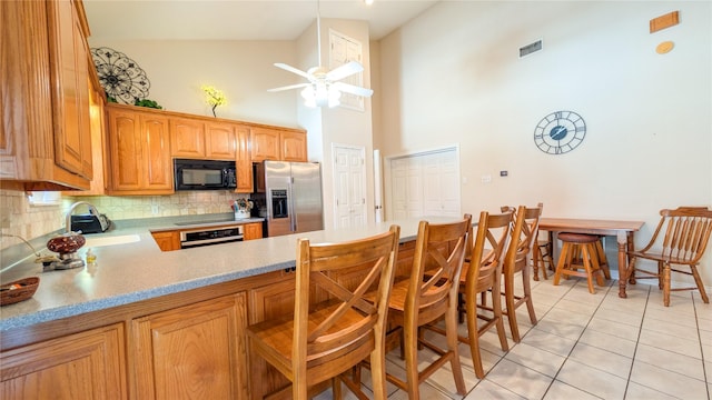 kitchen with a sink, visible vents, light countertops, backsplash, and black appliances