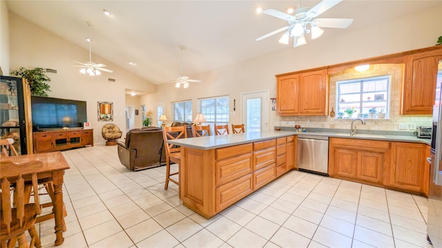 kitchen with light tile patterned floors, stainless steel dishwasher, open floor plan, a sink, and a peninsula