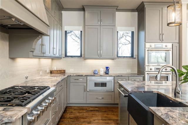 kitchen featuring stainless steel appliances, custom range hood, gray cabinets, and a sink