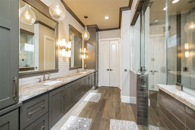 full bath with wood finished floors, a sink, ornamental molding, tasteful backsplash, and a stall shower