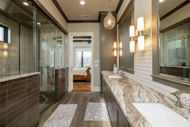 bathroom with ornamental molding, a stall shower, a sink, and wood finished floors