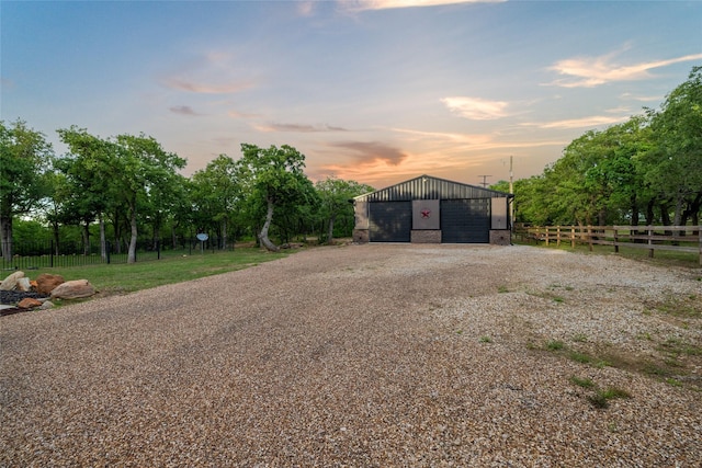 view of front facade featuring an outbuilding, driveway, fence, and a garage