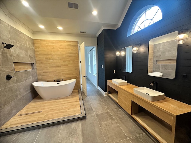 bathroom with a soaking tub, visible vents, a sink, and double vanity