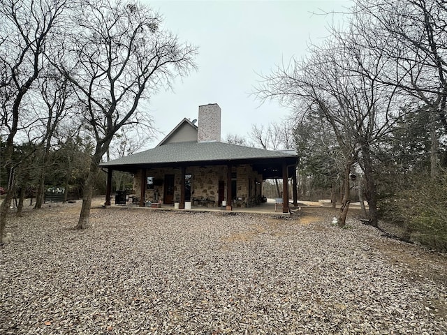 rear view of house featuring a shingled roof and a chimney