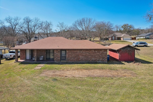 rear view of house featuring a shingled roof, a lawn, and brick siding