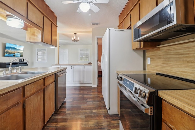 kitchen with dark wood-style flooring, a sink, light countertops, appliances with stainless steel finishes, and brown cabinets