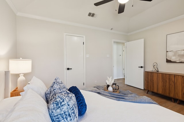 bedroom with ornamental molding, wood finished floors, visible vents, and a ceiling fan