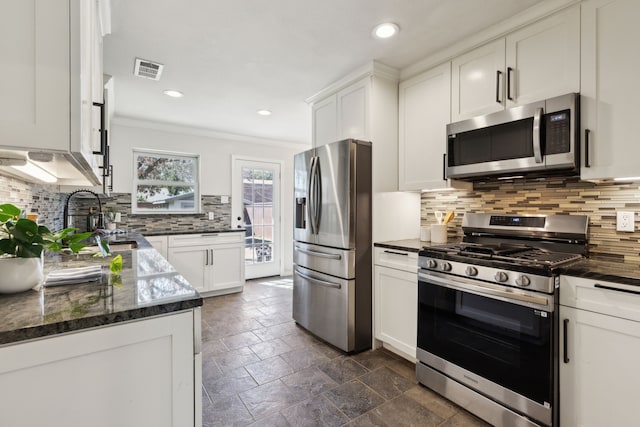 kitchen with stainless steel appliances, stone tile flooring, visible vents, ornamental molding, and white cabinetry