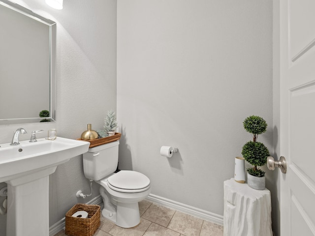 bathroom featuring baseboards, a sink, toilet, and tile patterned floors