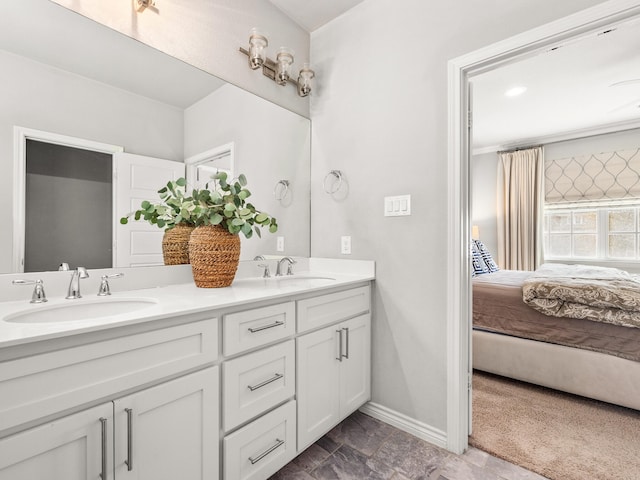 bathroom featuring double vanity, baseboards, a sink, and ensuite bathroom