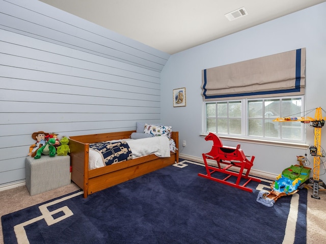 bedroom with wood walls, carpet, visible vents, and baseboards