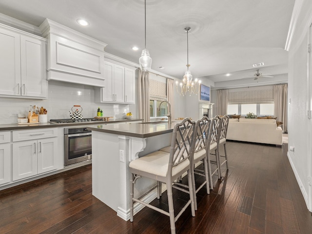 kitchen featuring dark countertops, dark wood-style floors, stainless steel appliances, and a sink