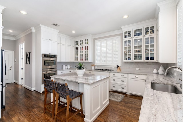 kitchen with stainless steel appliances, visible vents, a sink, and dark wood-type flooring