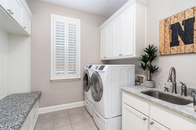 laundry room featuring light tile patterned floors, cabinet space, a sink, washer and dryer, and baseboards