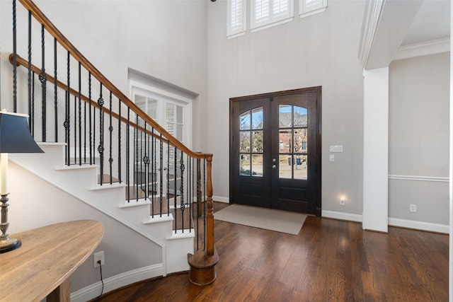 entrance foyer featuring baseboards, stairway, wood finished floors, crown molding, and french doors