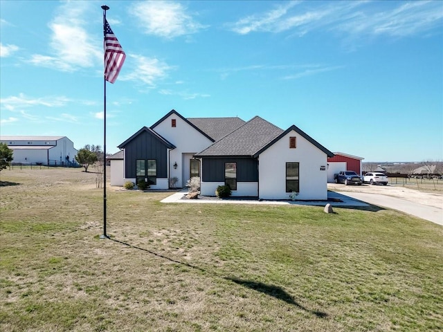 modern farmhouse style home featuring a shingled roof, board and batten siding, and a front yard